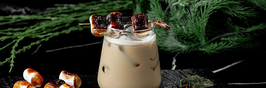 Koktail White Russian s opraženými marshmallows a kúskami ľadu podávaný na kamennej doske