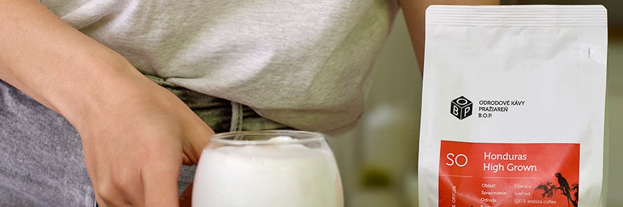 Pohár s cappuccinom inverso s hustou mliečnou penou položený na stole