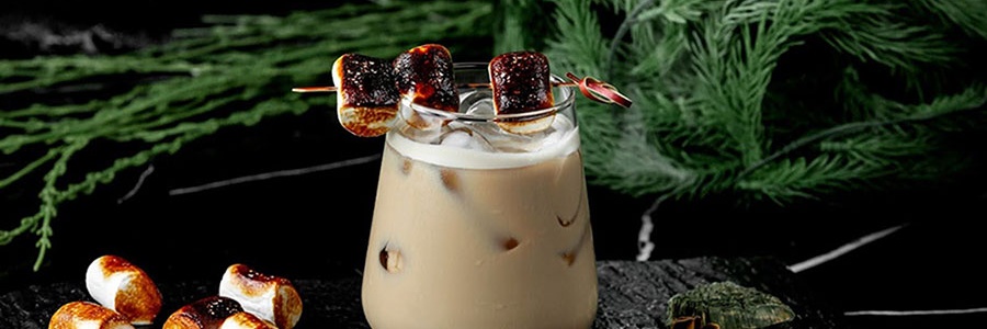 Koktail White Russian s opraženými marshmallows a kúskami ľadu podávaný na kamennej doske