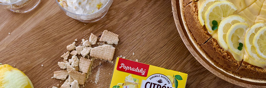 Citrónový cheesecake podávaný vo forme torty a v pohári na drevenom stole s citrónovým čajom popradské