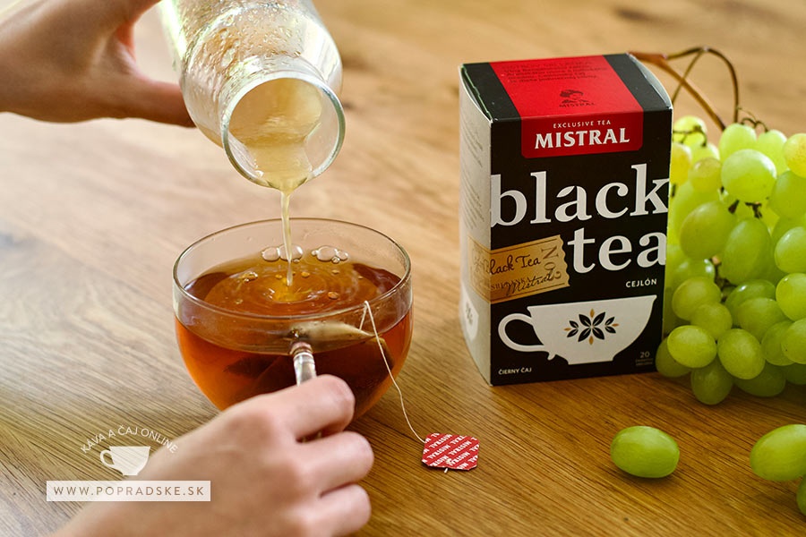 Žena leje domáci hroznový sirup do čierneho čaju Mistral na drevenom stole
