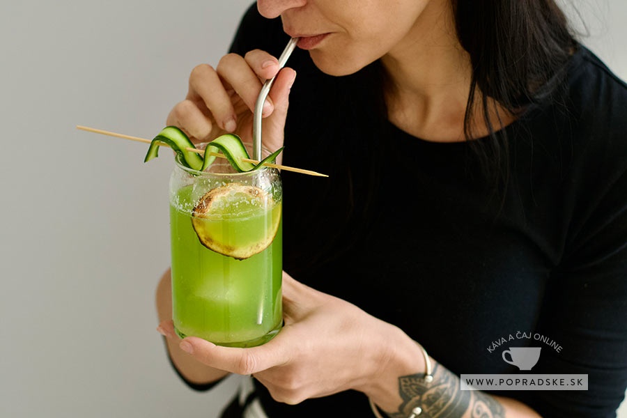Žena pije domácu uhorkovú limonádu s ľadom, citrónom a ozdobou z čerstvej uhorky