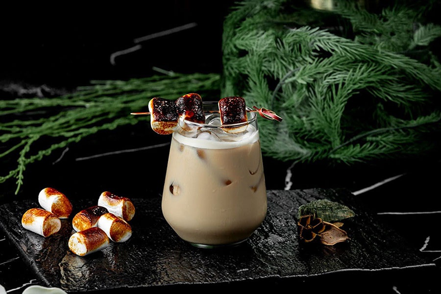 Koktail White Russian s opraženými marshmallows a kúskami ľadu podávaný na kamennej doske
