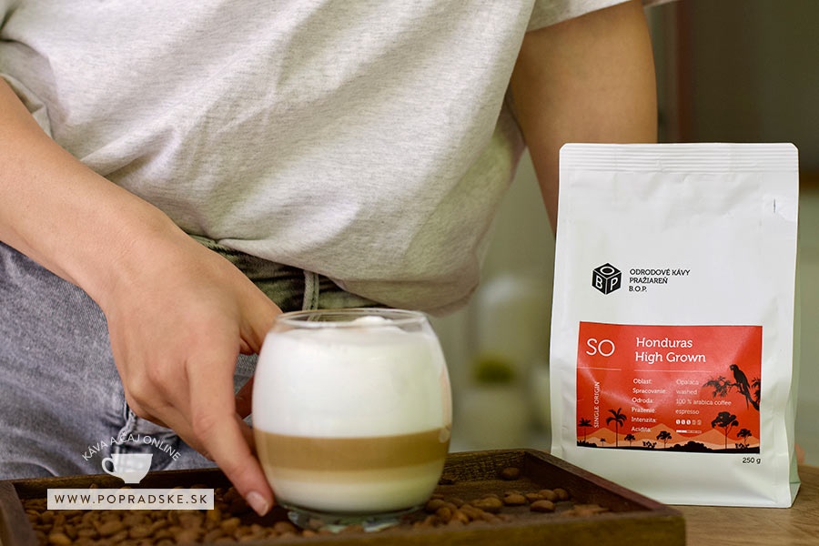 Pohár s cappuccinom inverso s hustou mliečnou penou položený na stole