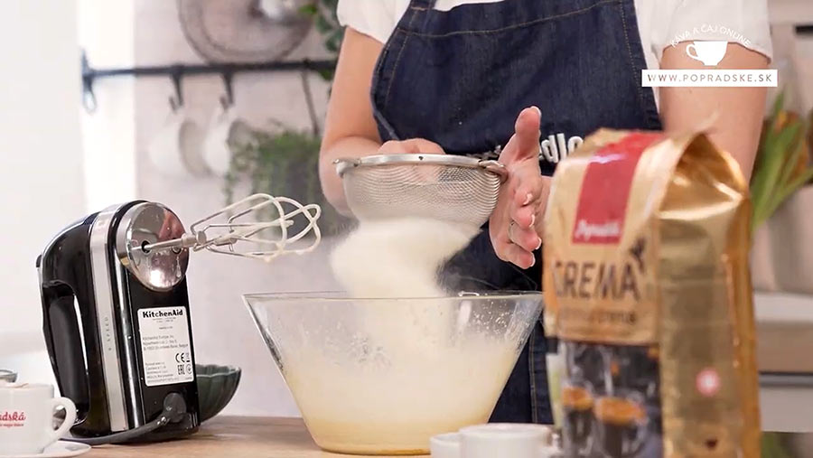 Ženské ruky pridávajúce sypké suroviny ku žĺtkovej zmesi na koláč oblíž prst