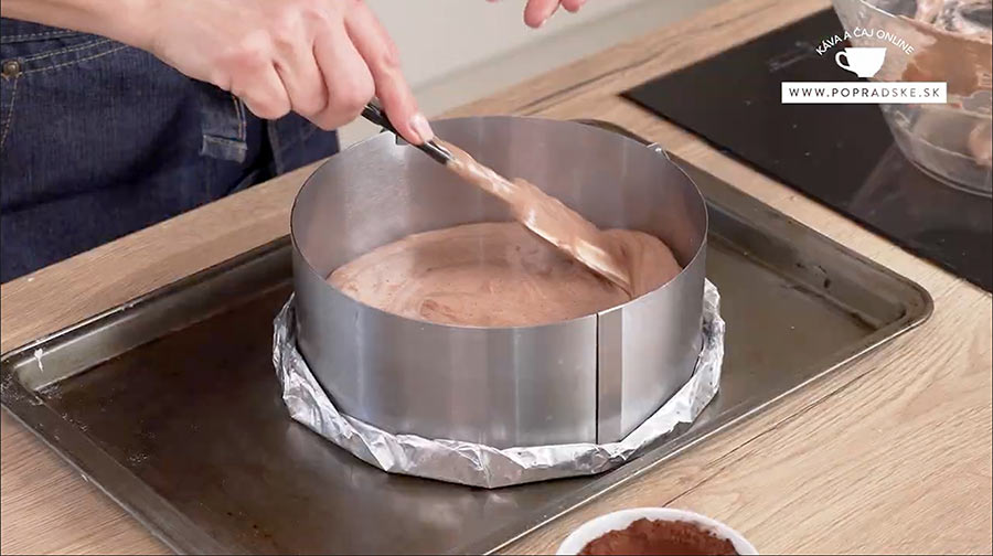 Ženské ruky rozotierajú cesto na koláč v sivej tortovej forme