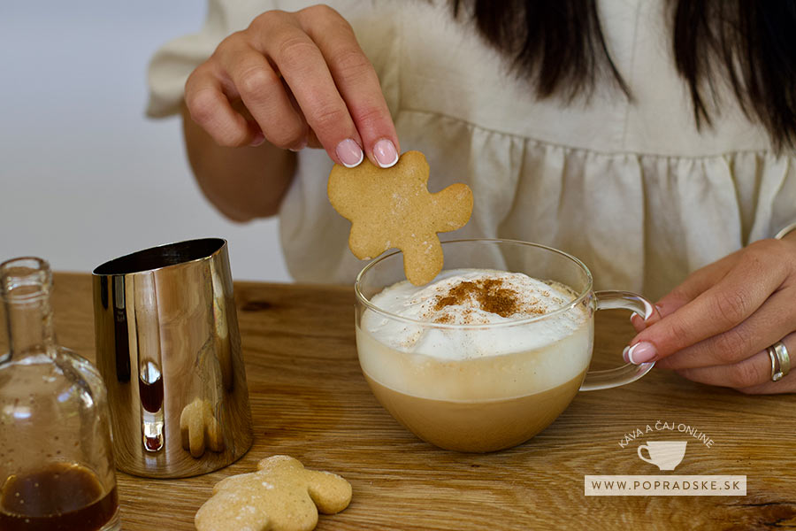 Žena si namáča perník do domáceho gingerbread latte v priehľadnej šálke