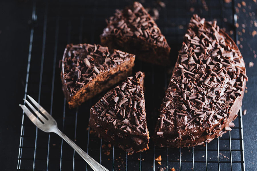 Šťavnatá čokoládová torta posypaná hoblinkami čokolády nakrájaná na kúsky, pripravená ako dezert k švédskej kávovej prestávke Fika